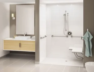 Accessible walk-in shower with white acrylic walls, stainless steel grab bars, fold-down shower seat, and handheld showerhead next to a modern floating wood vanity with vessel sink