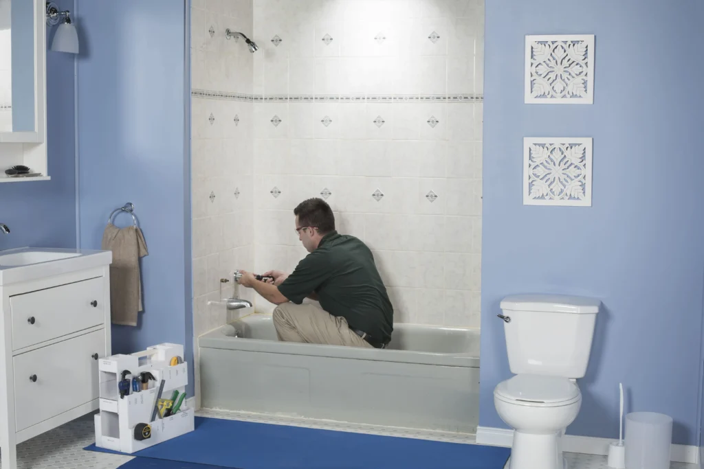 Bath Fitter technician preparing and cleaning existing bathtub surfaces before acrylic liner installation in a residential bathroom